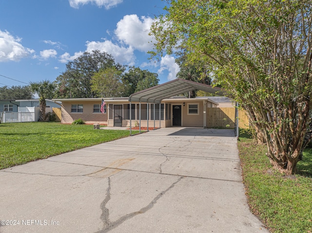 view of front of property featuring a sunroom, a carport, and a front yard