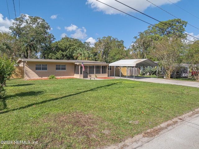 ranch-style home with a front yard, a sunroom, and a carport