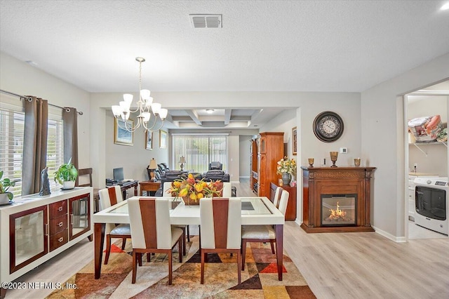 dining area featuring a textured ceiling, washer / clothes dryer, light hardwood / wood-style floors, beamed ceiling, and a chandelier