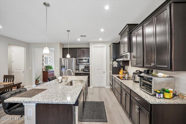 kitchen with stainless steel appliances, light hardwood / wood-style floors, sink, tasteful backsplash, and pendant lighting