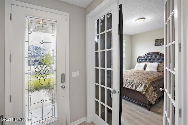 entryway featuring french doors, a textured ceiling, and light wood-type flooring