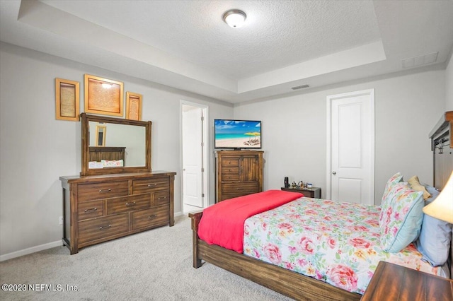 carpeted bedroom with a textured ceiling and a raised ceiling