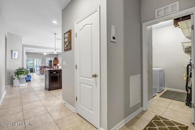 hallway featuring independent washer and dryer and light tile patterned floors