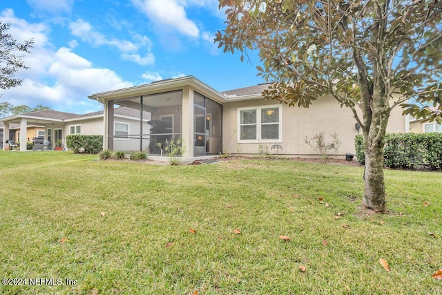 back of house featuring a lawn and a sunroom