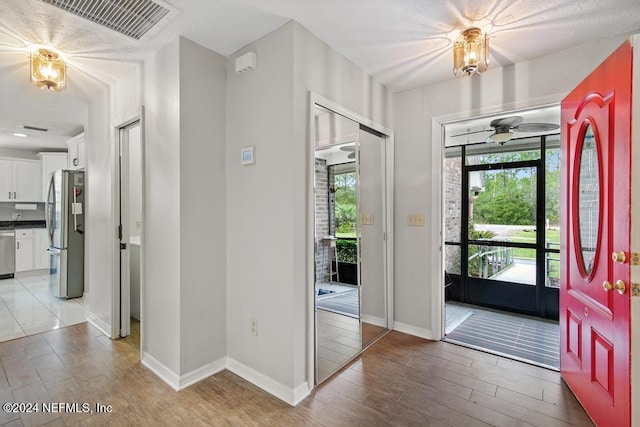 foyer entrance with ceiling fan and light wood-type flooring