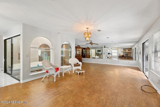 living area with ceiling fan with notable chandelier and light hardwood / wood-style floors