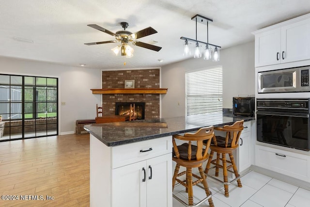 kitchen with white cabinets, black oven, stainless steel microwave, and plenty of natural light