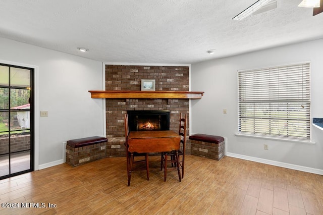 miscellaneous room featuring light hardwood / wood-style floors, a textured ceiling, and a brick fireplace