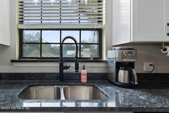 interior details with white cabinets, sink, and dark stone counters