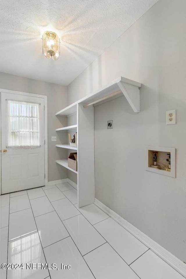 laundry room featuring electric dryer hookup, hookup for a washing machine, light tile patterned floors, and a textured ceiling