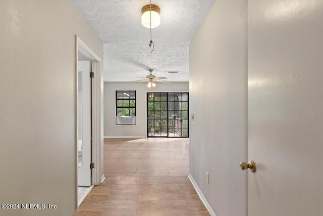 hallway featuring light hardwood / wood-style floors and a textured ceiling