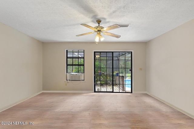 unfurnished room with ceiling fan, light hardwood / wood-style floors, a textured ceiling, and cooling unit