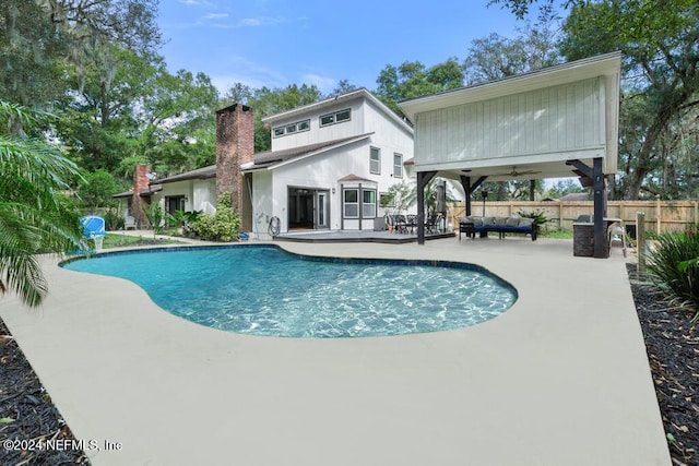 back of property featuring ceiling fan, a patio area, a fenced in pool, and an outdoor living space