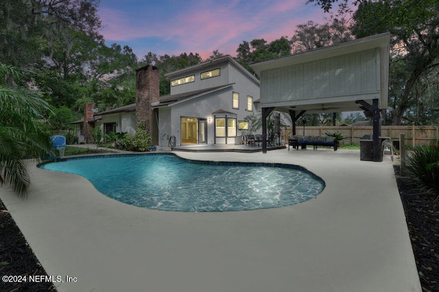 pool at dusk with a patio area, ceiling fan, and an outdoor living space