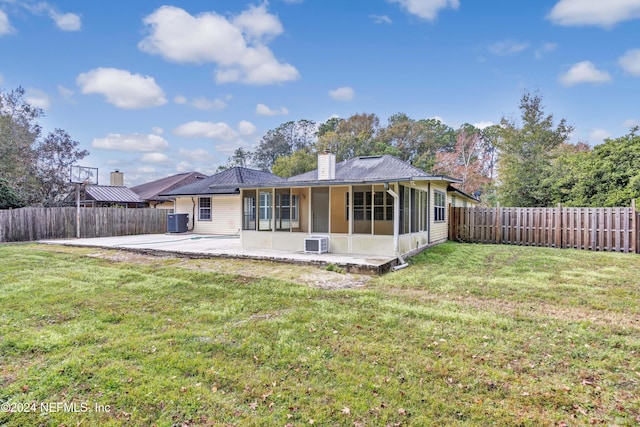 rear view of house featuring central AC unit, a sunroom, a patio, and a lawn