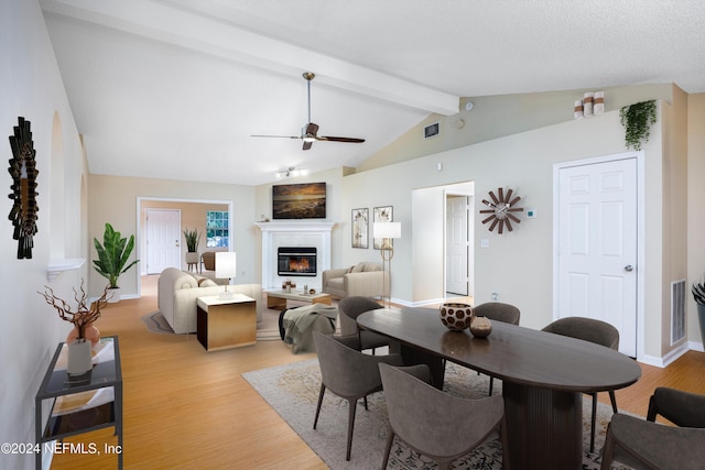 dining room with ceiling fan, lofted ceiling with beams, and light wood-type flooring