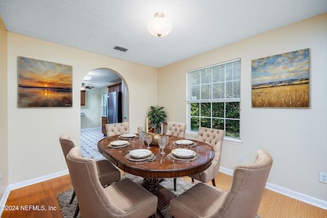 dining room with ceiling fan, light hardwood / wood-style floors, and a textured ceiling