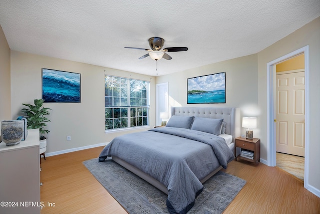 bedroom with a textured ceiling, light wood-type flooring, and ceiling fan