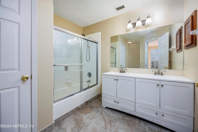 bathroom featuring vanity, enclosed tub / shower combo, and a textured ceiling