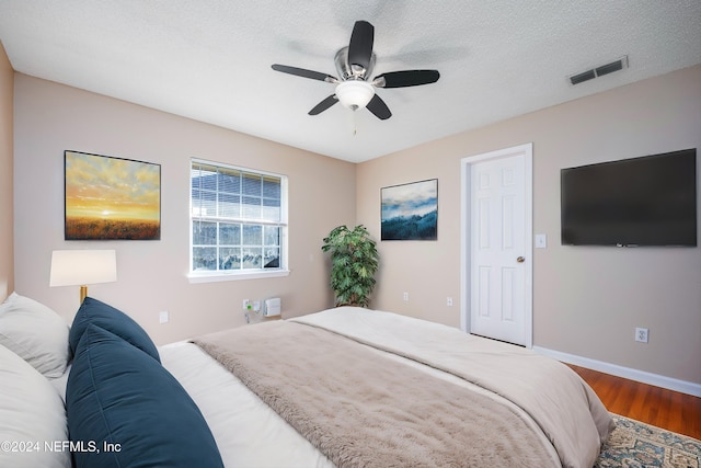 bedroom with ceiling fan, wood-type flooring, and a textured ceiling