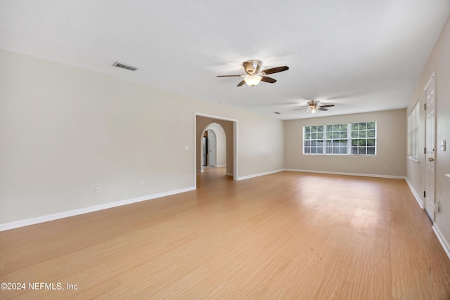 empty room with ceiling fan, light hardwood / wood-style flooring, and a textured ceiling