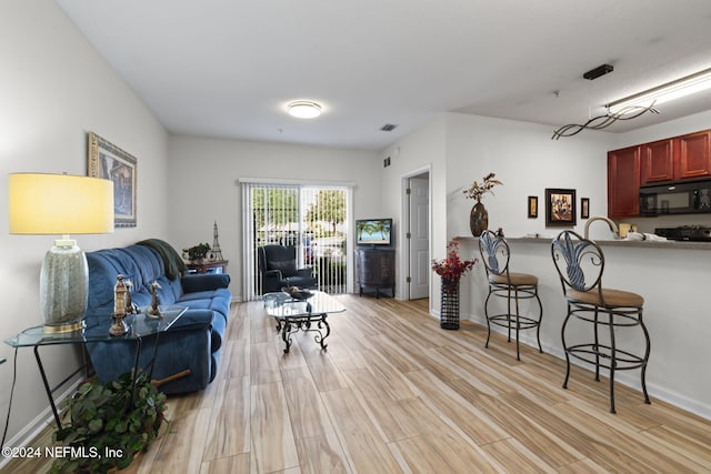 living area featuring light wood-type flooring, visible vents, and baseboards