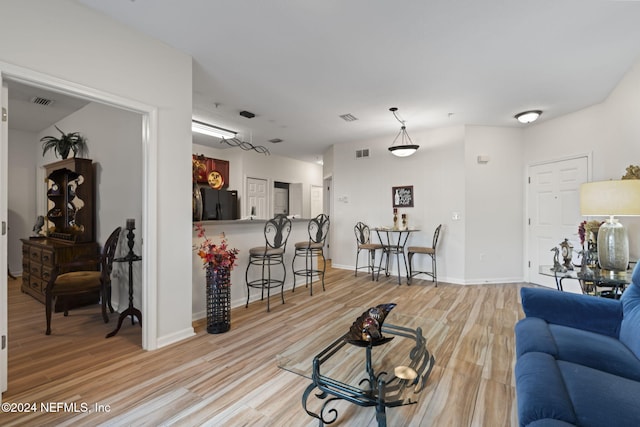 living room featuring light wood finished floors, baseboards, and visible vents