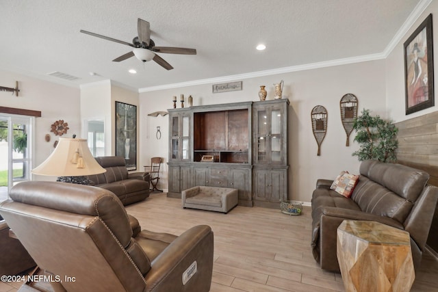 living room with light wood-type flooring, a textured ceiling, ceiling fan, and ornamental molding