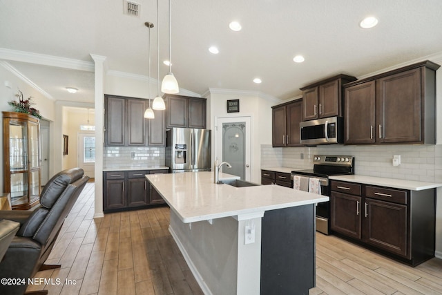 kitchen featuring pendant lighting, sink, ornamental molding, appliances with stainless steel finishes, and light hardwood / wood-style floors