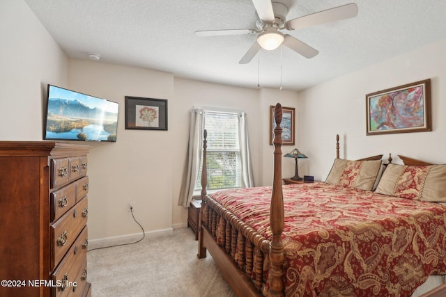 bedroom with ceiling fan, light colored carpet, and a textured ceiling