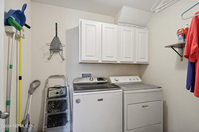 clothes washing area featuring cabinets, a textured ceiling, and washing machine and clothes dryer