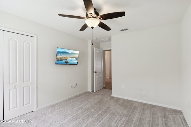 unfurnished bedroom featuring ceiling fan, a closet, and light carpet