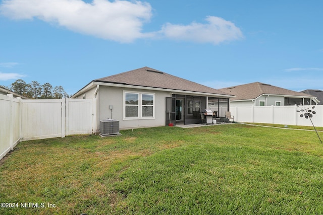 back of property featuring a sunroom, cooling unit, a patio area, and a lawn