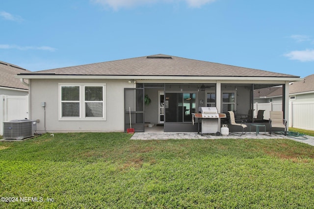 rear view of house with a lawn, a sunroom, and cooling unit