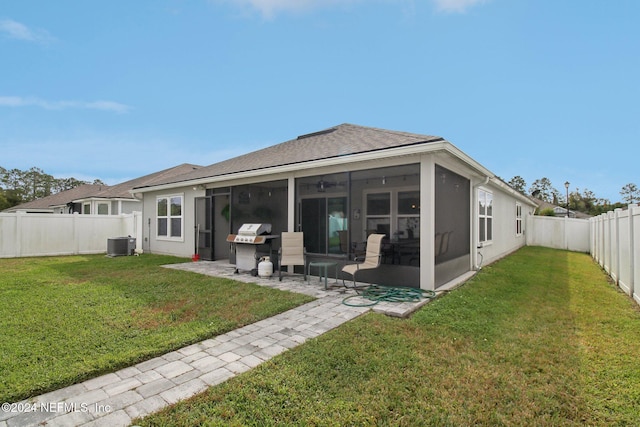 back of property with a sunroom, cooling unit, and a yard