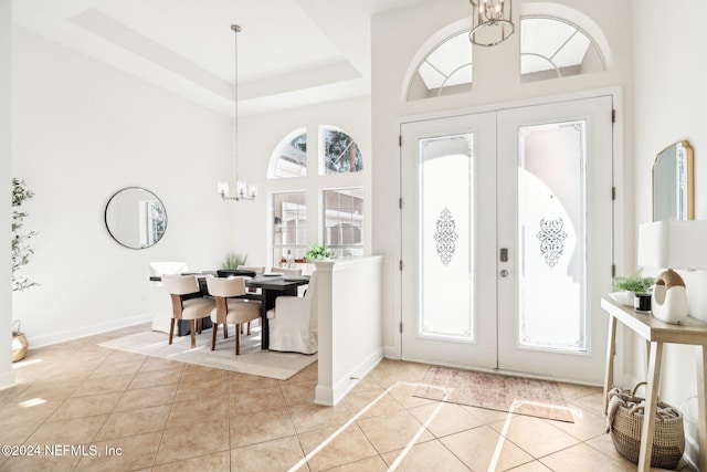 tiled entrance foyer featuring a high ceiling, an inviting chandelier, and french doors