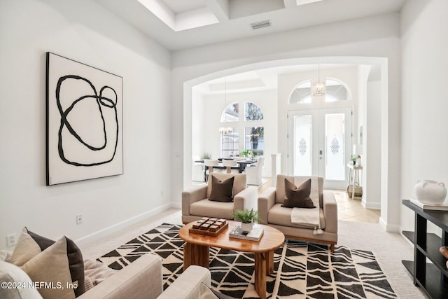 carpeted living room featuring french doors and a chandelier