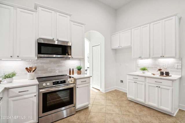 kitchen featuring tasteful backsplash, light tile patterned flooring, white cabinets, and stainless steel appliances