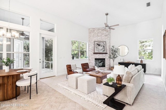 tiled living room with a fireplace and ceiling fan with notable chandelier