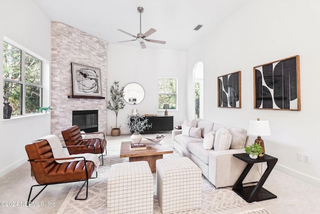 living room with a stone fireplace, ceiling fan, high vaulted ceiling, and light colored carpet