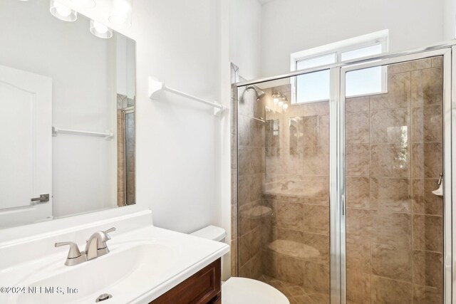 bathroom featuring vanity, toilet, and an enclosed shower