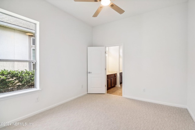 unfurnished bedroom with ensuite bath, ceiling fan, and light carpet