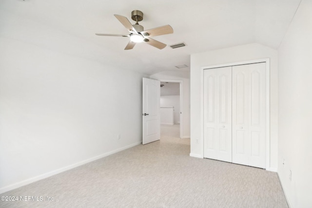 unfurnished bedroom featuring light carpet, a closet, lofted ceiling, and ceiling fan