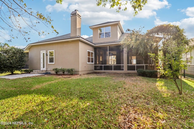 back of house featuring a lawn and a sunroom