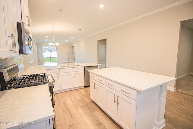 kitchen with a center island with sink, sink, white cabinetry, hanging light fixtures, and stainless steel appliances