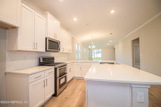 kitchen featuring a kitchen island, crown molding, light wood-type flooring, appliances with stainless steel finishes, and white cabinets