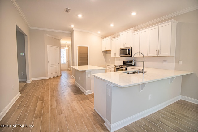 kitchen with kitchen peninsula, light wood-type flooring, appliances with stainless steel finishes, a breakfast bar area, and white cabinets