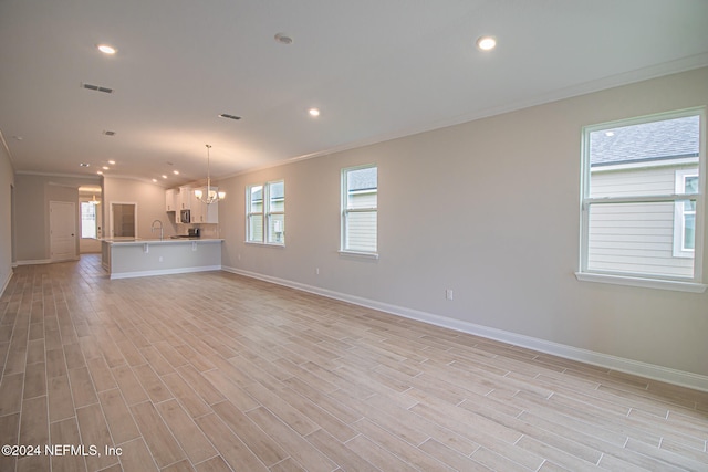 unfurnished living room featuring light wood-type flooring, sink, a chandelier, and ornamental molding