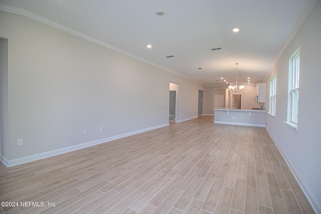 unfurnished living room with light wood-type flooring, crown molding, and a chandelier