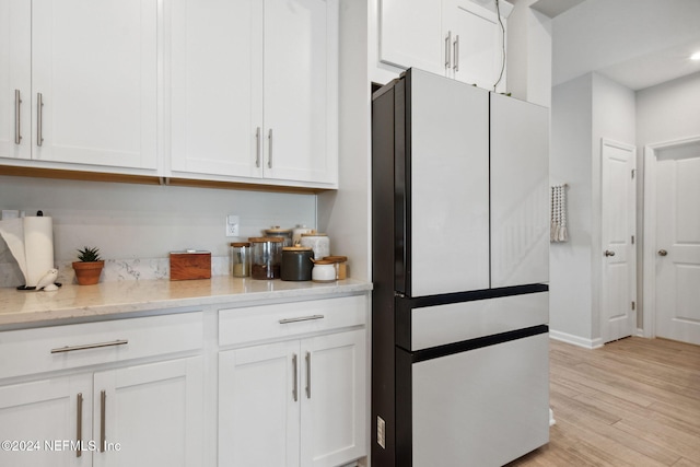 kitchen featuring white cabinetry, refrigerator, light hardwood / wood-style floors, and light stone counters